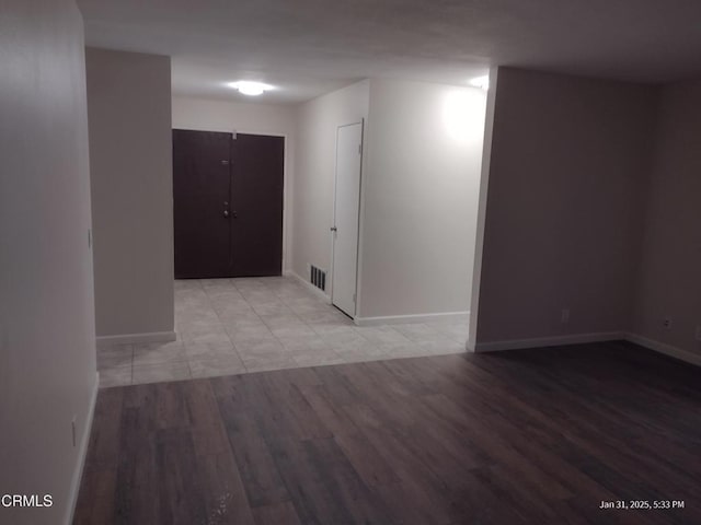 spare room with light wood finished floors, visible vents, and baseboards