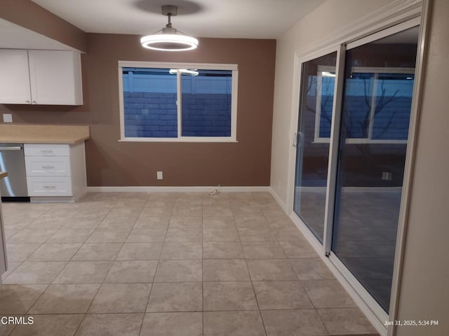 unfurnished dining area featuring built in desk, baseboards, and light tile patterned floors