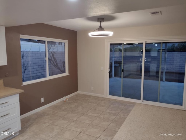 unfurnished dining area featuring baseboards and visible vents