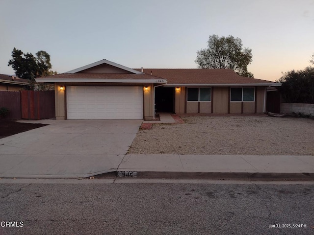 ranch-style house with concrete driveway, board and batten siding, an attached garage, and fence