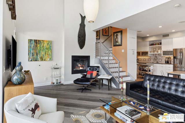 living room with a towering ceiling and dark hardwood / wood-style floors