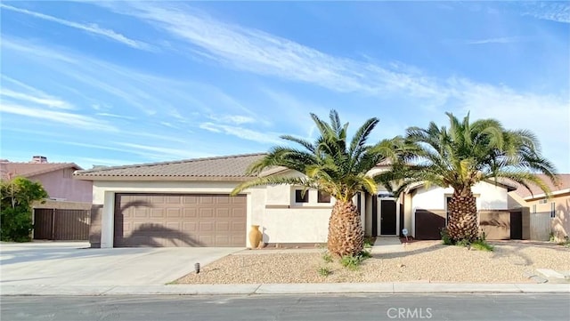 81060 Paloma Cir, Indio, CA 92201 - view of front of home featuring driveway, a garage, stucco siding, a tiled roof, and fence