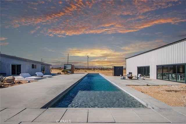 pool at dusk featuring a patio