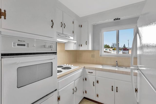 kitchen featuring sink, white cabinetry, tile counters, white appliances, and decorative backsplash