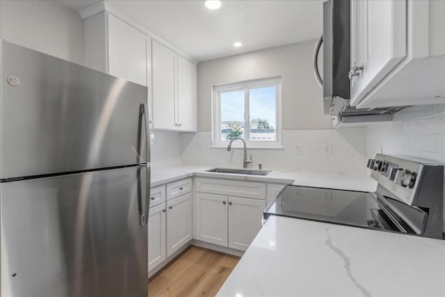 kitchen featuring white cabinetry, sink, light stone counters, and appliances with stainless steel finishes