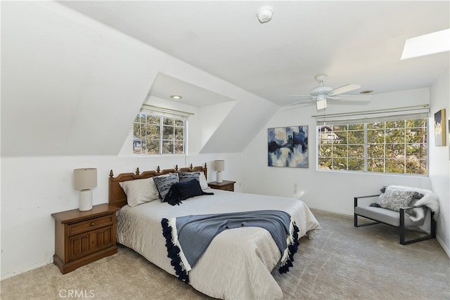 bedroom featuring ceiling fan, light colored carpet, and vaulted ceiling with skylight