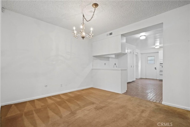 unfurnished dining area with dark colored carpet, a chandelier, and a textured ceiling