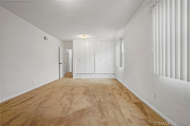 unfurnished bedroom featuring light colored carpet and a textured ceiling