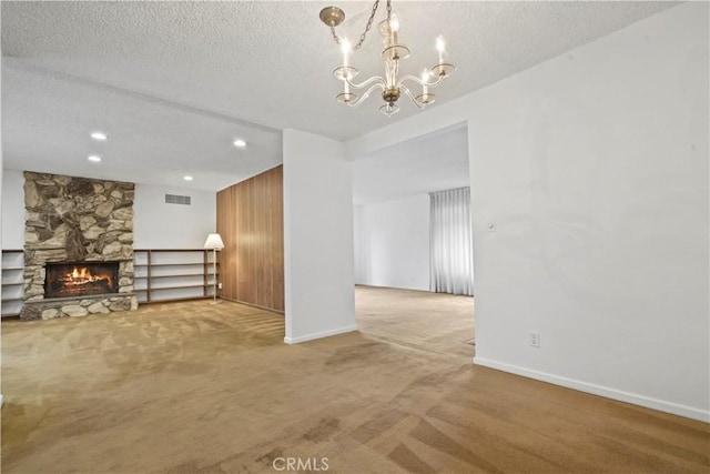 unfurnished living room with a fireplace, a chandelier, carpet floors, and a textured ceiling