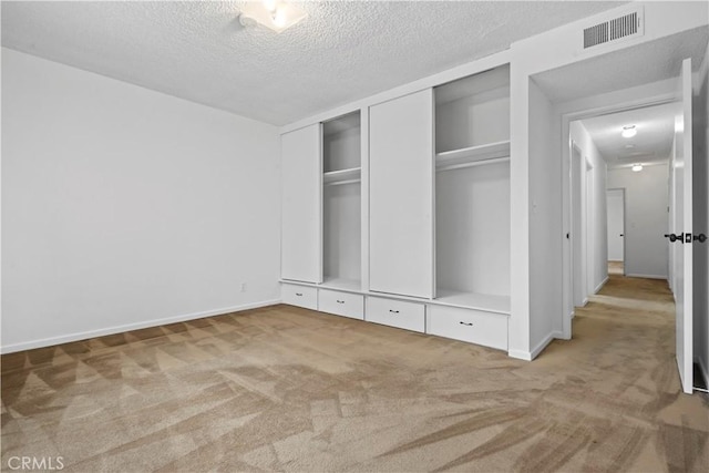 unfurnished bedroom with two closets, a textured ceiling, and carpet flooring