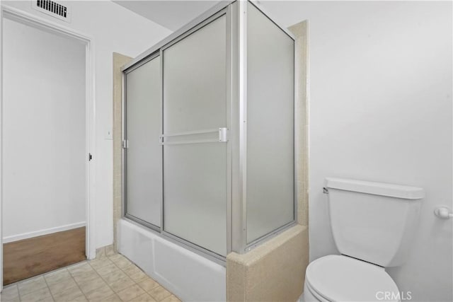 bathroom featuring combined bath / shower with glass door and toilet