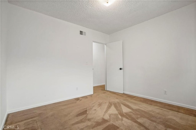 empty room with light carpet and a textured ceiling