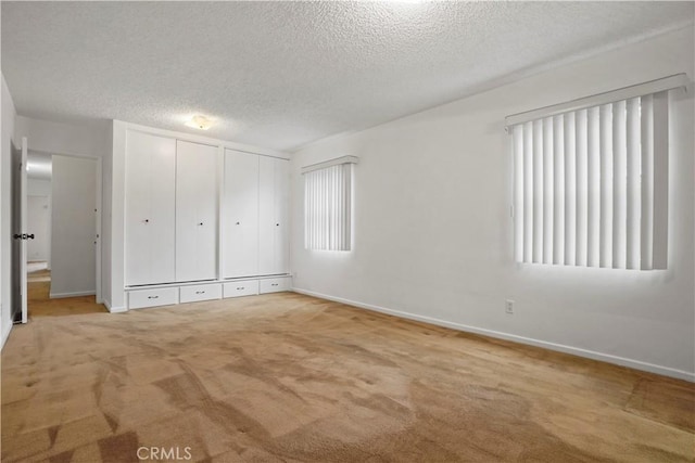 unfurnished bedroom featuring light carpet, a textured ceiling, and a closet