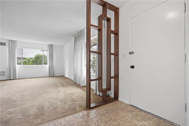 foyer entrance featuring light carpet and a textured ceiling