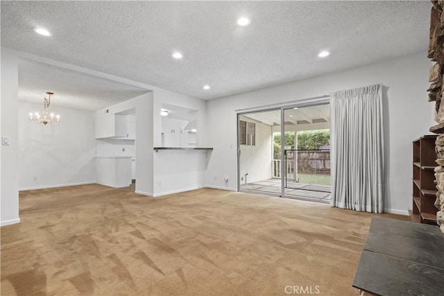 unfurnished living room featuring an inviting chandelier, light colored carpet, and a textured ceiling