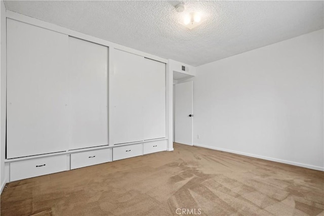 unfurnished bedroom with carpet floors, two closets, and a textured ceiling