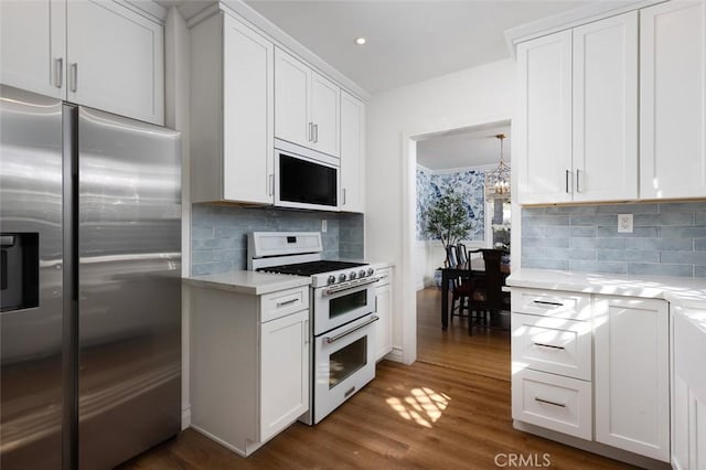 kitchen featuring a notable chandelier, white appliances, dark wood-type flooring, and white cabinets