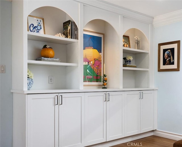 bar featuring ornamental molding, hardwood / wood-style floors, built in features, and white cabinets