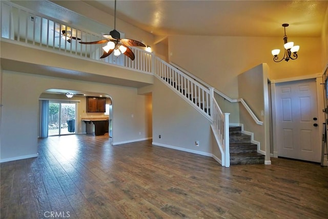 foyer featuring dark wood-type flooring, ceiling fan with notable chandelier, and high vaulted ceiling