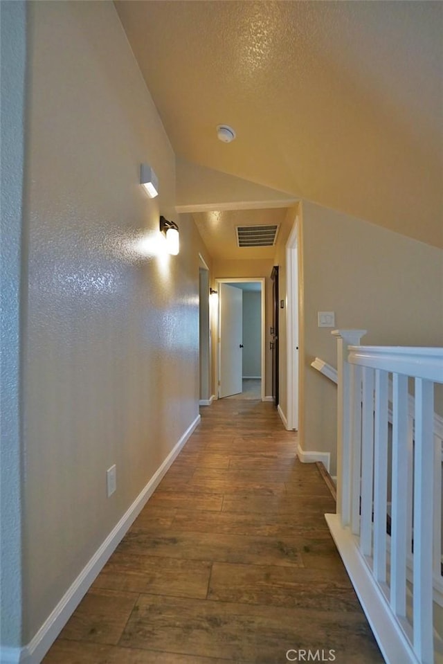 hall featuring vaulted ceiling and dark wood-type flooring