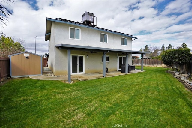 back of house with a storage shed, a yard, and a patio