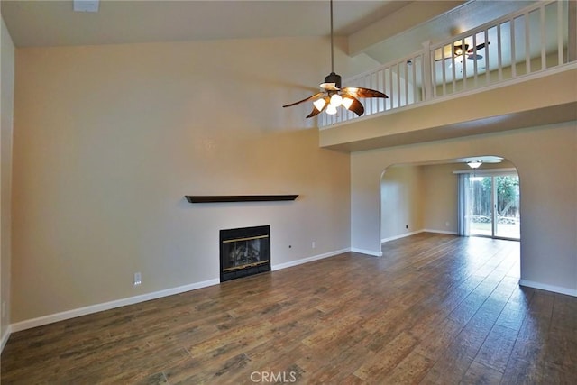 unfurnished living room featuring dark wood-type flooring, high vaulted ceiling, and ceiling fan