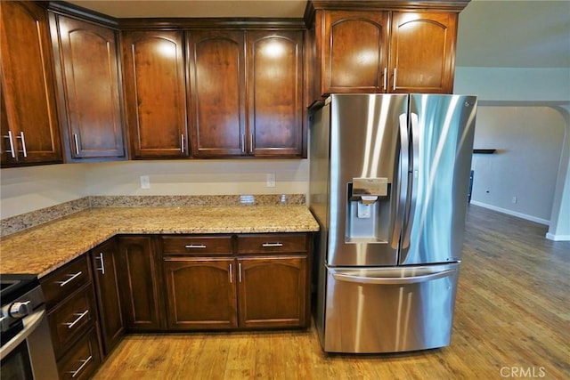 kitchen featuring light stone countertops, appliances with stainless steel finishes, and light wood-type flooring