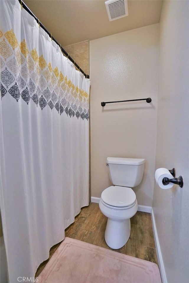 bathroom with hardwood / wood-style floors, toilet, and a shower with shower curtain