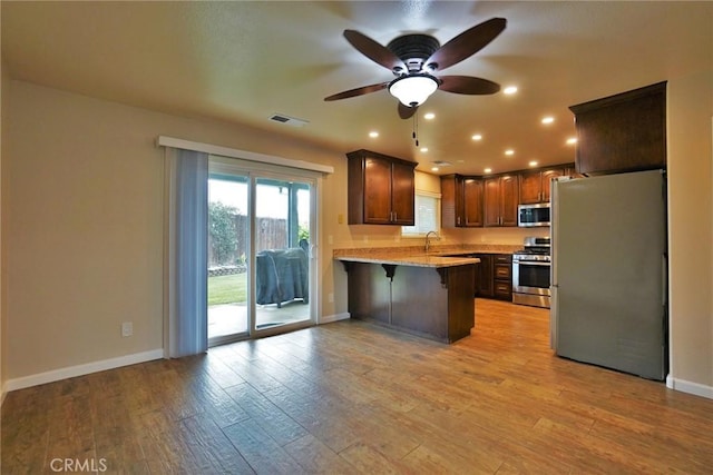 kitchen with light hardwood / wood-style flooring, a breakfast bar area, stainless steel appliances, and kitchen peninsula