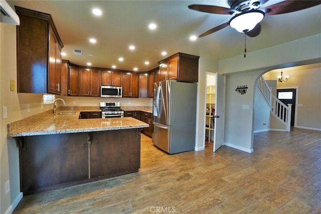 kitchen featuring sink, light hardwood / wood-style flooring, kitchen peninsula, stainless steel appliances, and light stone countertops