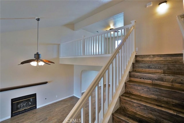 staircase featuring ceiling fan, wood-type flooring, and high vaulted ceiling