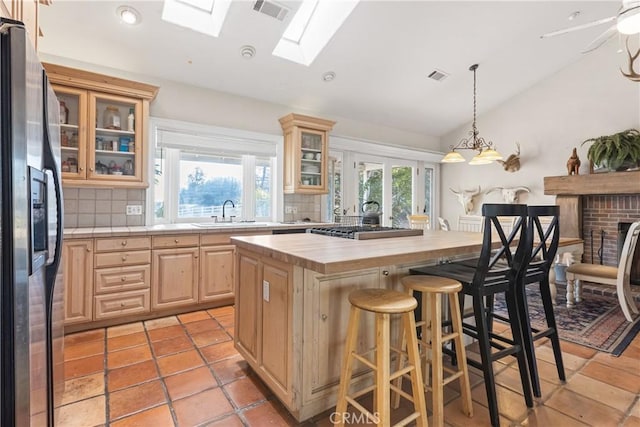 kitchen featuring a kitchen island, appliances with stainless steel finishes, wood counters, a kitchen breakfast bar, and light brown cabinets