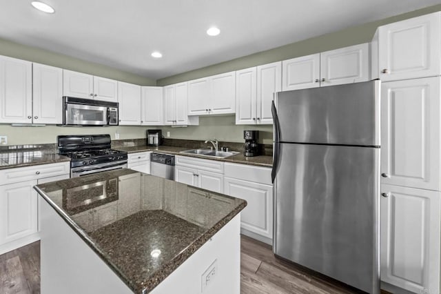 kitchen with dark stone countertops, a kitchen island, white cabinets, and appliances with stainless steel finishes