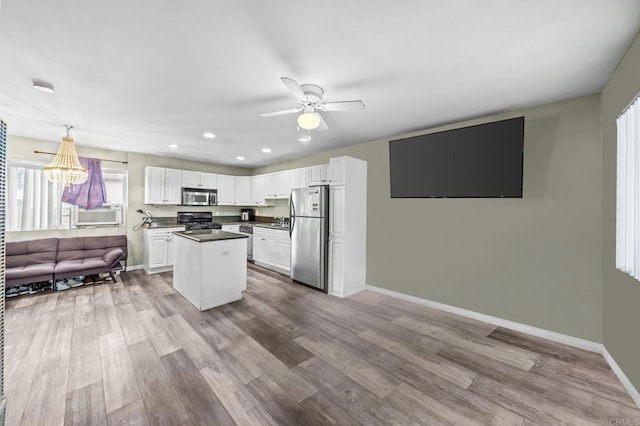 kitchen with a kitchen island, white cabinetry, sink, stainless steel appliances, and light hardwood / wood-style flooring