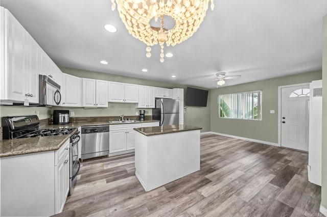 kitchen with a kitchen island, appliances with stainless steel finishes, sink, and white cabinets