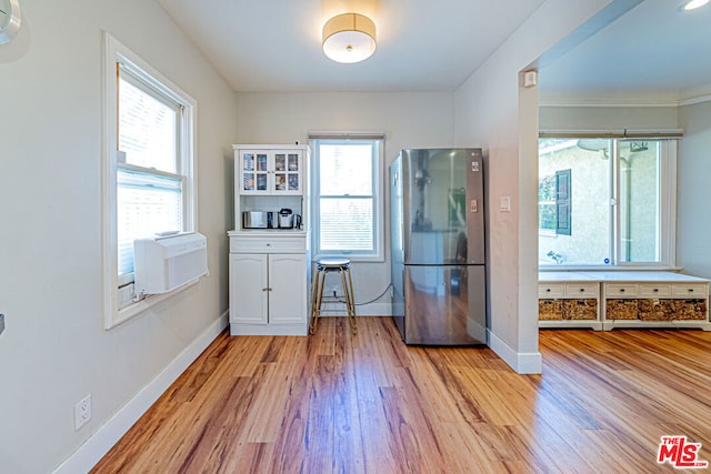 interior space featuring a healthy amount of sunlight, light wood-type flooring, white cabinets, and stainless steel refrigerator