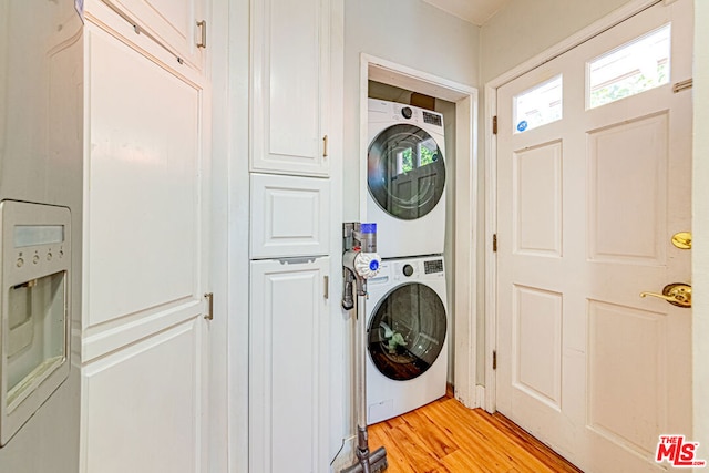 laundry area featuring stacked washer / dryer and light hardwood / wood-style flooring