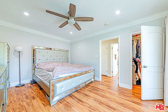 bedroom with crown molding, a spacious closet, ceiling fan, and light hardwood / wood-style flooring