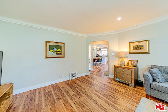 living area with crown molding and light hardwood / wood-style flooring