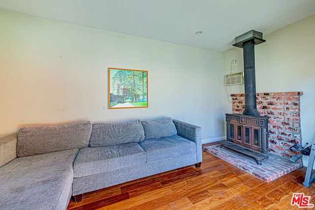 living room featuring hardwood / wood-style flooring, a wall unit AC, and a wood stove