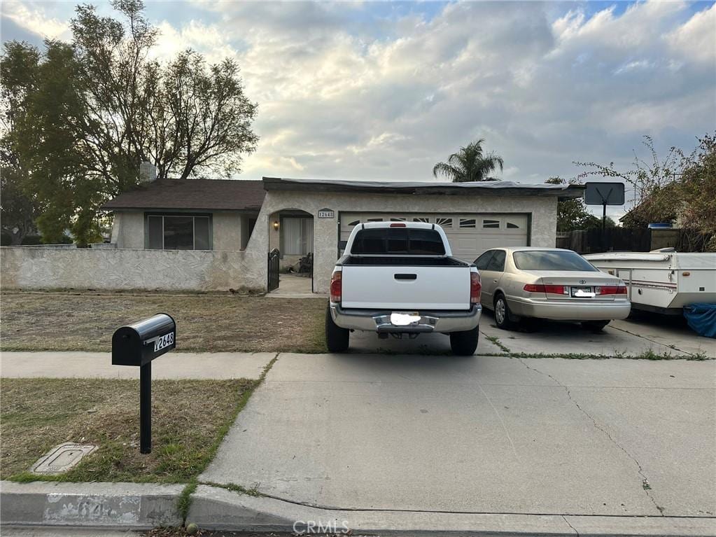 ranch-style house featuring driveway, an attached garage, and stucco siding