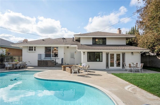 rear view of property featuring a fenced in pool, a patio, and french doors