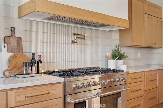 kitchen with light brown cabinetry, backsplash, double oven range, light stone counters, and custom range hood