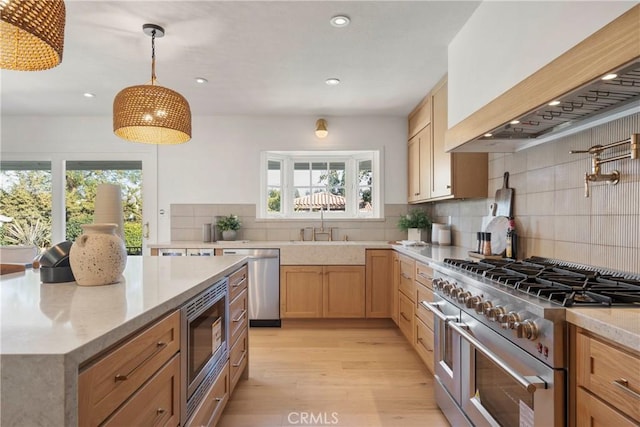 kitchen featuring appliances with stainless steel finishes, plenty of natural light, sink, and decorative light fixtures