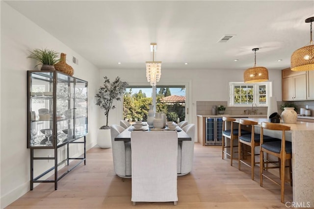 kitchen featuring pendant lighting, sink, wine cooler, and light hardwood / wood-style floors