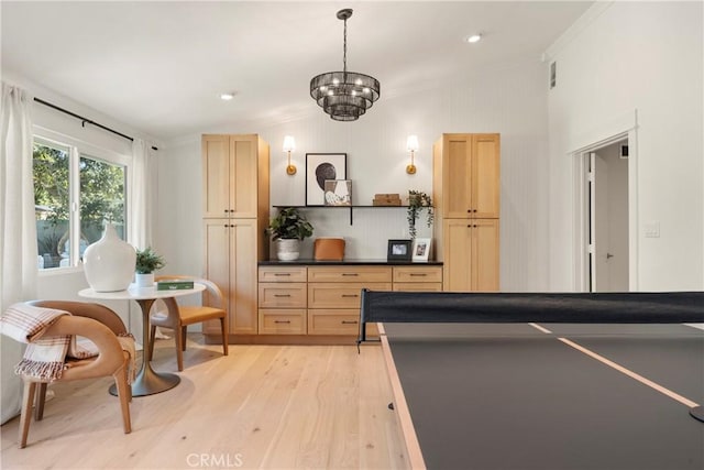 rec room with a notable chandelier, crown molding, and light hardwood / wood-style flooring