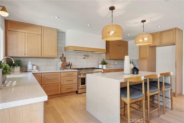 kitchen with sink, hanging light fixtures, a center island, stainless steel range, and custom range hood