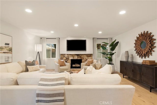 living room featuring a stone fireplace and light hardwood / wood-style floors