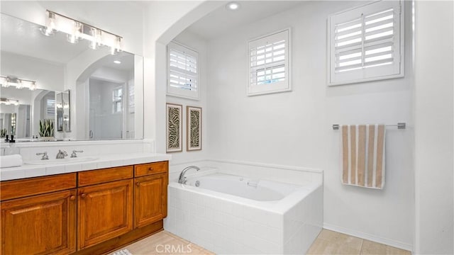 bathroom with vanity and tiled bath