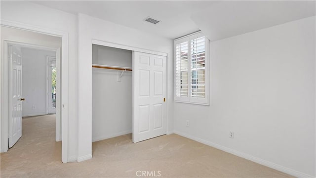 unfurnished bedroom featuring light colored carpet and a closet